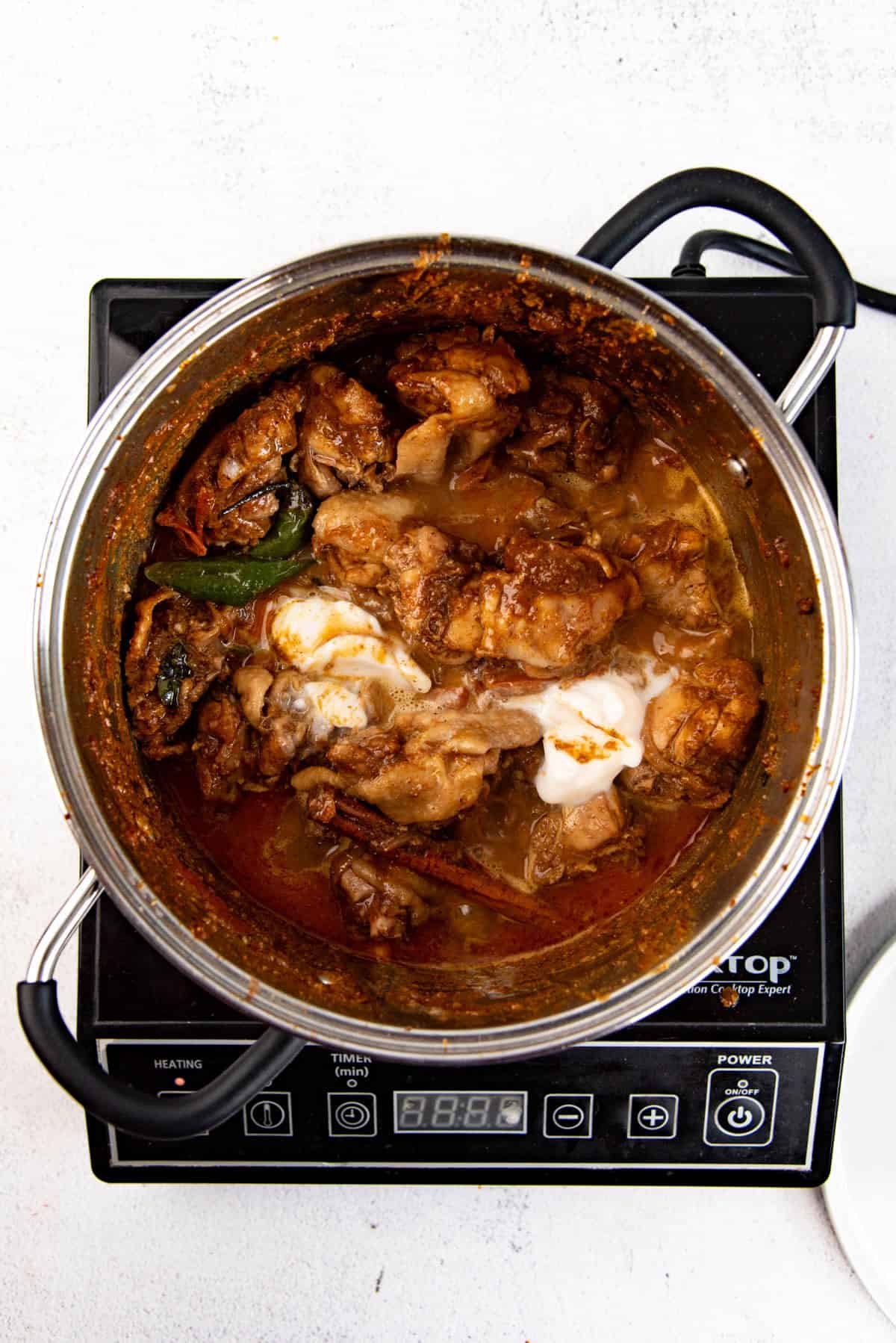 Adding water and coconut milk to the chicken curry.