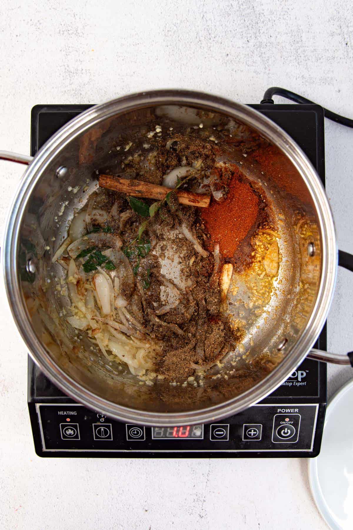 Adding the spices to the softened onions along with curry leaves.