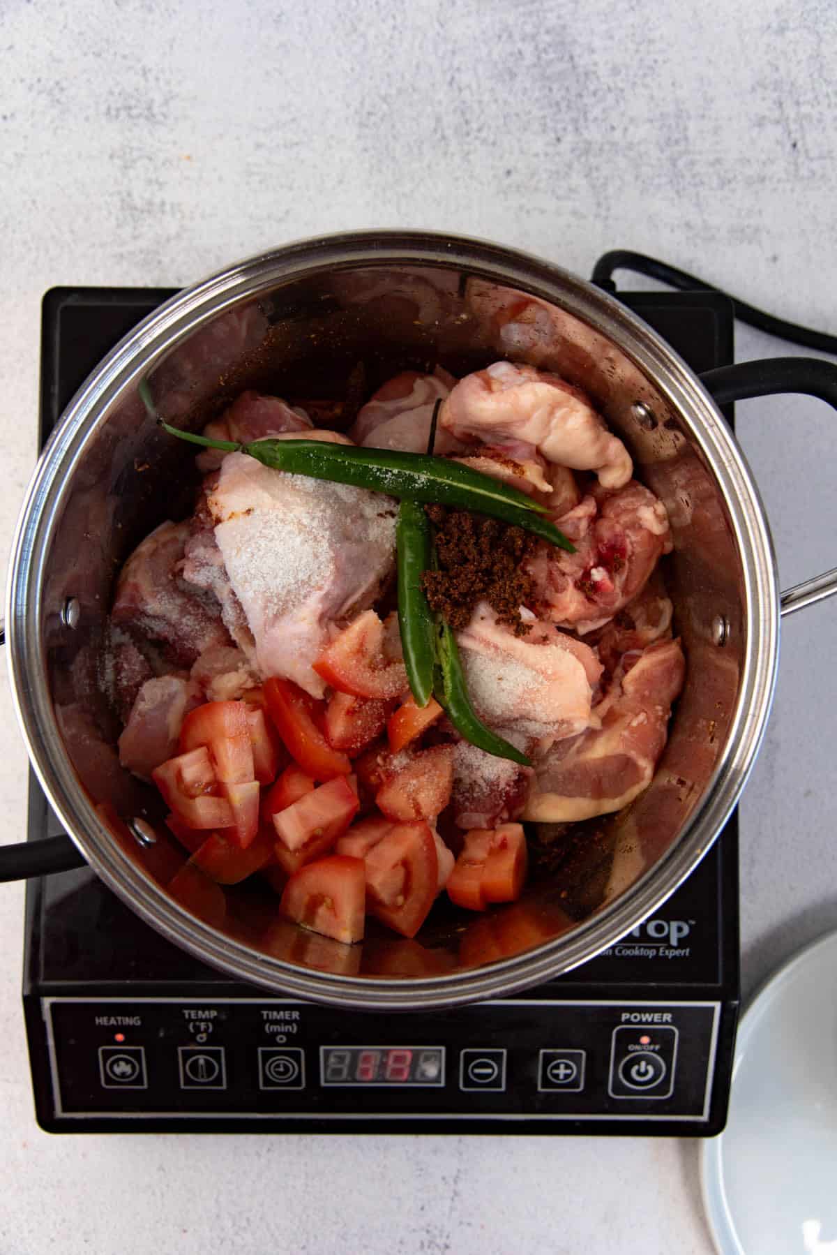 Adding the chicken and tomatoes to the curry base to make an easy authentic chicken curry.