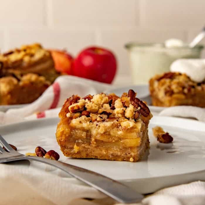 An apple pie bar on a plate, with more in the background.