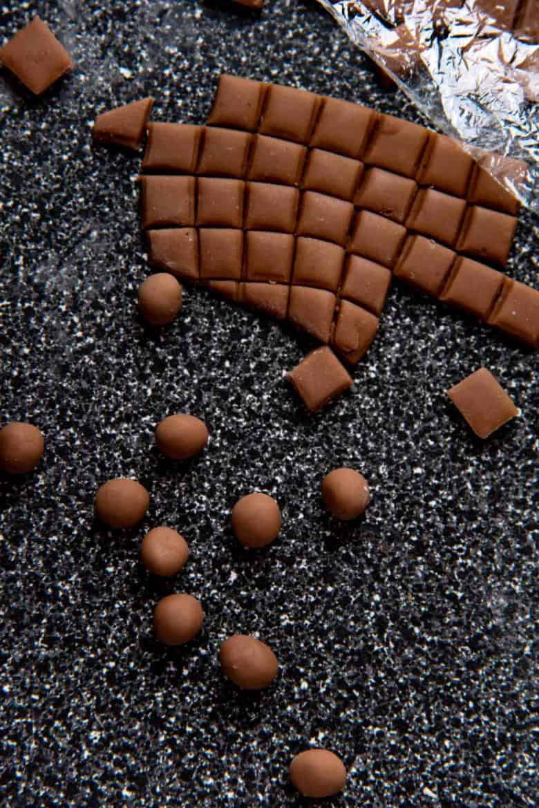 An image of the cut up square pieces of dough being rolled up to form balls