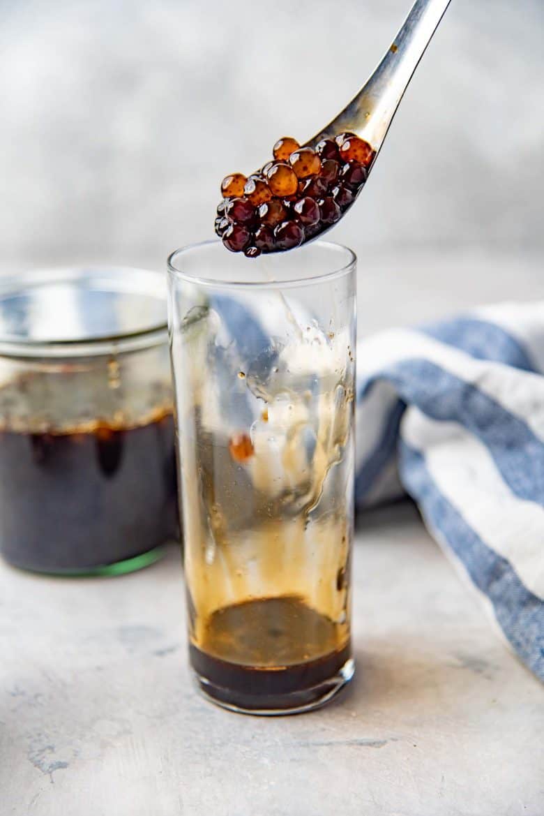 Adding the brown sugar boba pearls to the glass