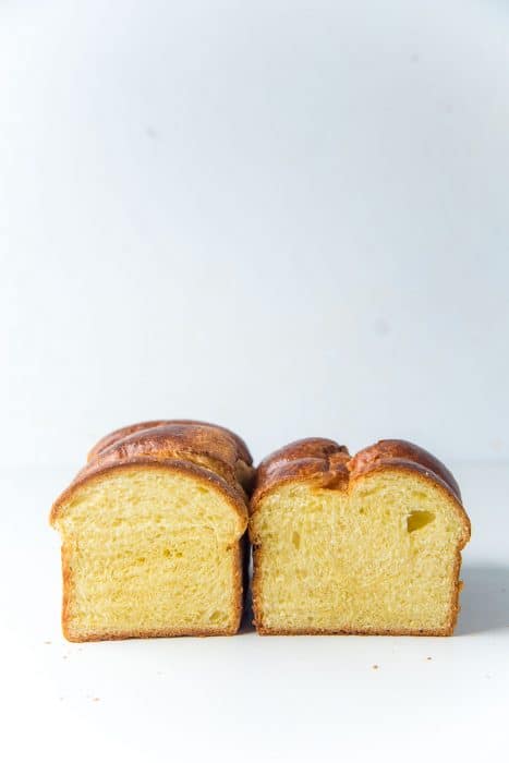 Two brioche loaves baked in two different sized loaf pans, cut in half to show their different sizes.