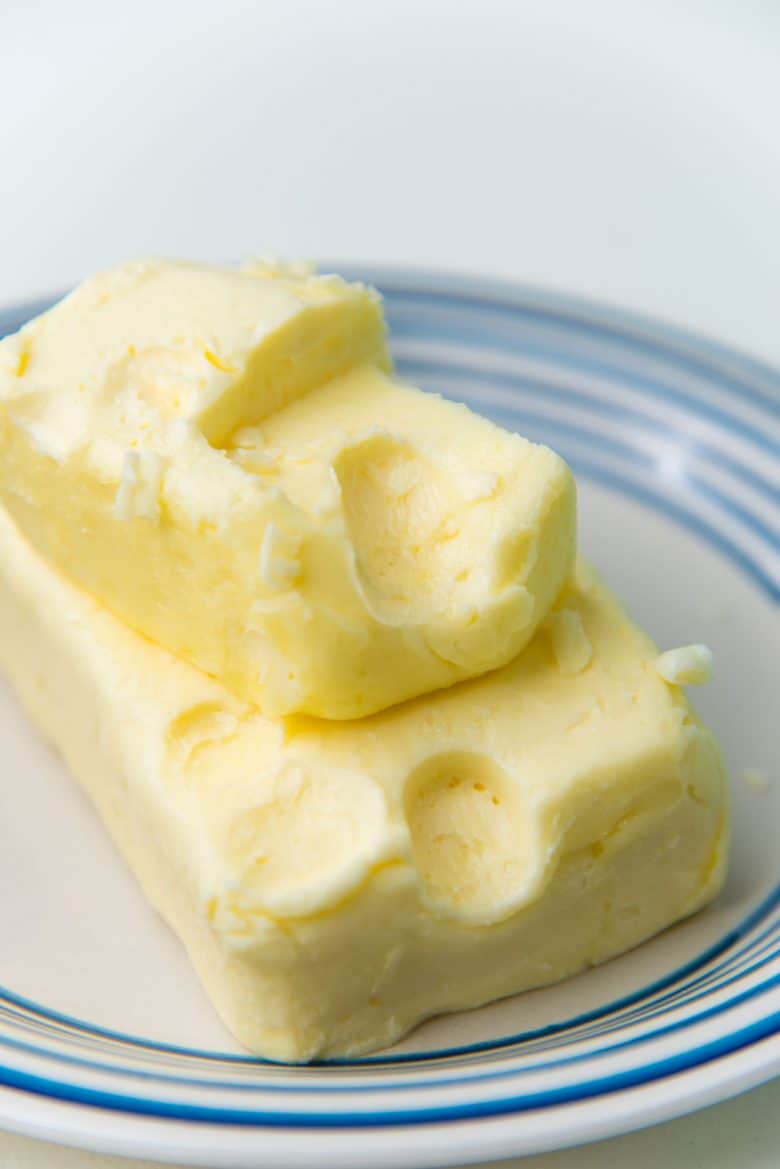 Softened butter on a small white plate with a finger indentation to show the butter is soft. 