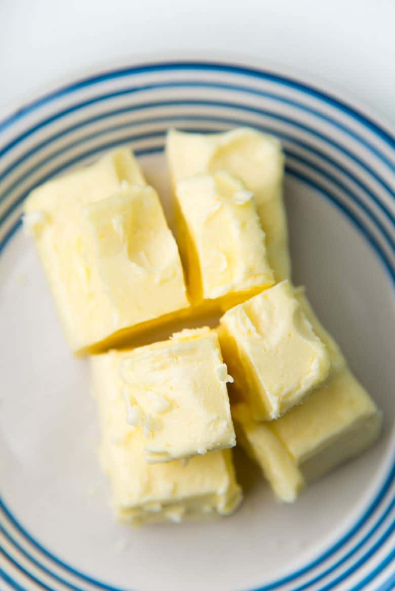 Butter roughly divided into 4 portions on a small white plate.