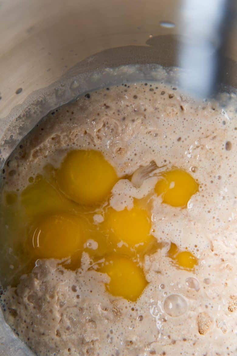 Adding eggs and other wet ingredients to yeast in a big mixer bowl.