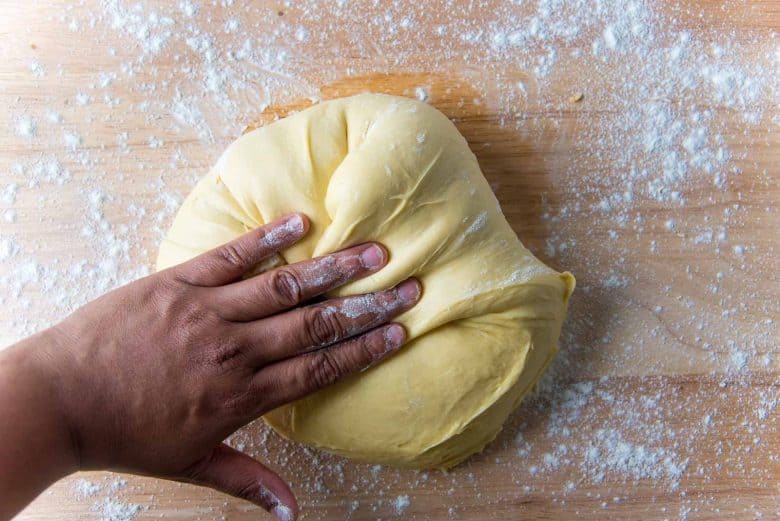 Folding the brioche dough by hand towards the middle on a lightly floured work surface.