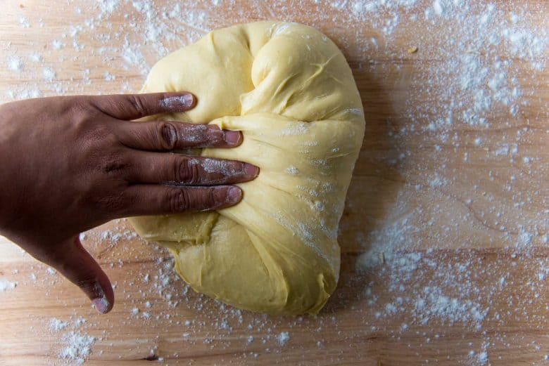 Folding the brioche dough by hand towards the middle on a lightly floured wood surface.