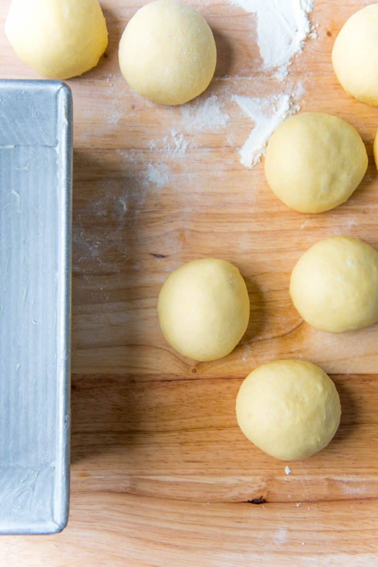 Several perfectly formed smooth round dough balls on a work surface.