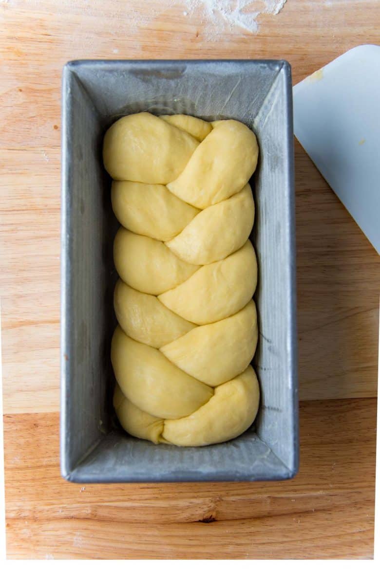 Braided bread loaf in a metal loaf pan before proofing.
