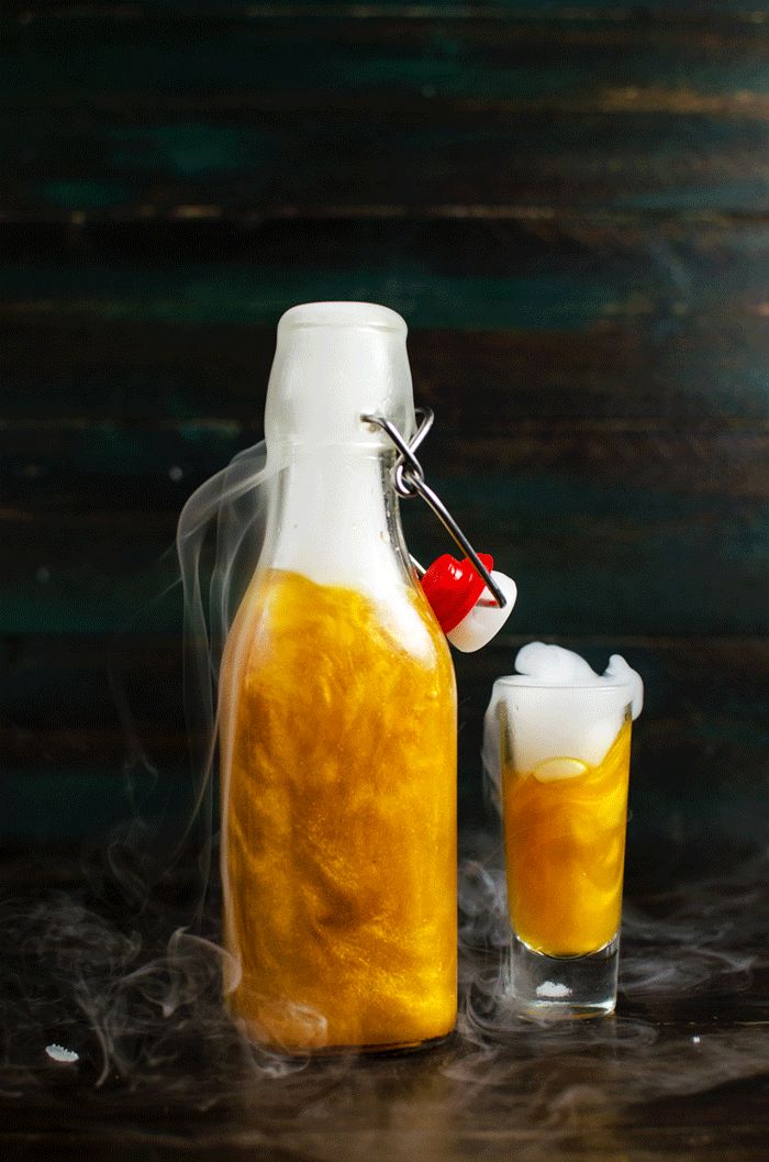 GIF of a bright gold shimmering liqueur bottle with liquid nitrogen-induced smoke coming from the top.