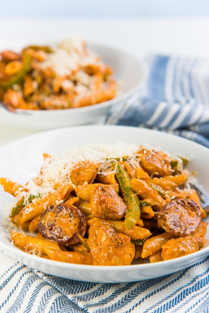 Creamy cajun chicken pasta with parmesan cheese on top served in a white bowl.