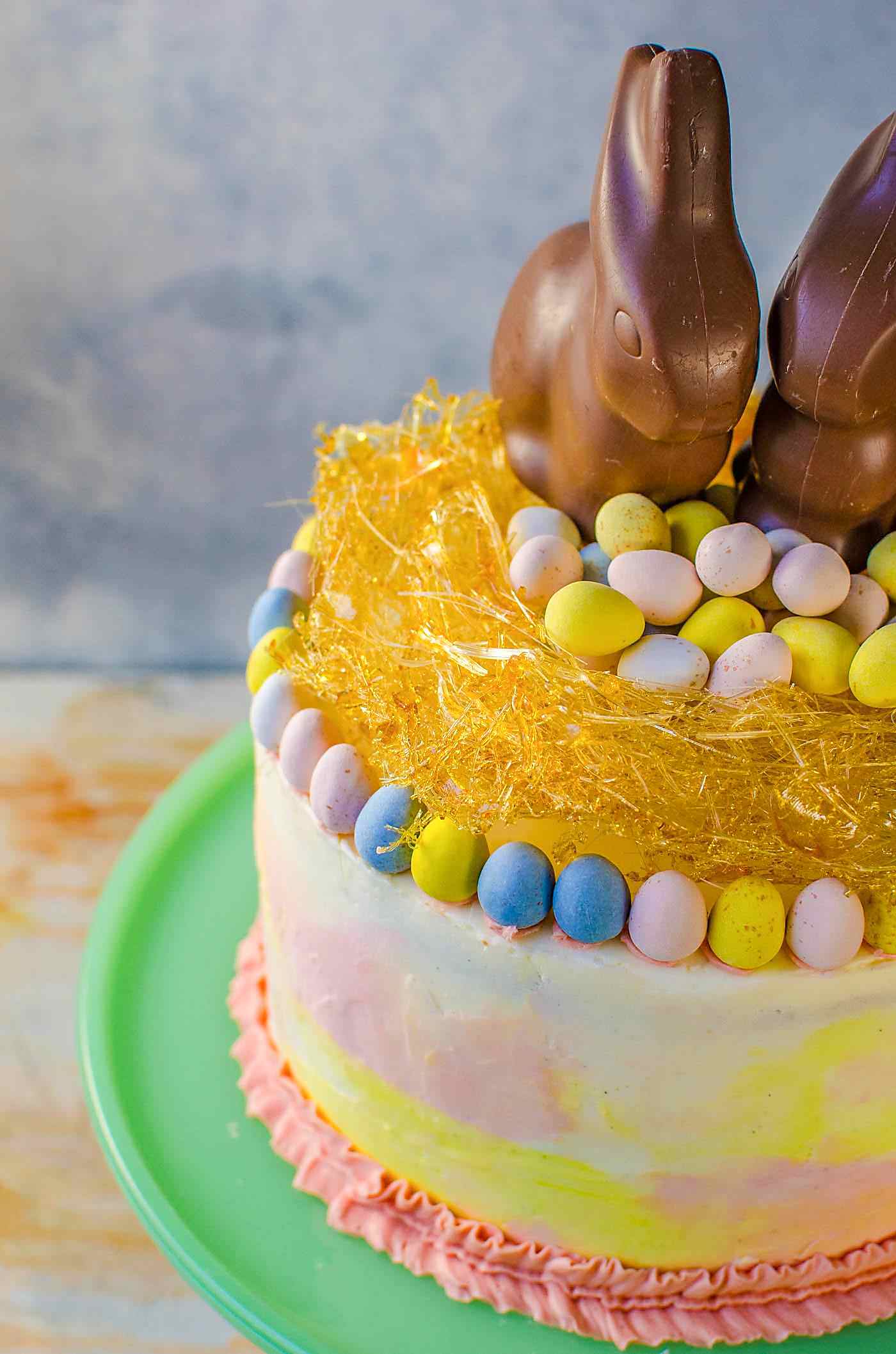 Chai and Vanilla Cake with soft, fluffy Vanilla Buttercream frosting - A spectacular swirled Easter cake with a gorgeous pastel watercolor effect, decorated with Easter eggs, chocolate bunnies and a caramelized nest on top! A sunny, happy and outrageously delicious cake to celebrate all of life's special occasions and nostalgic memories!