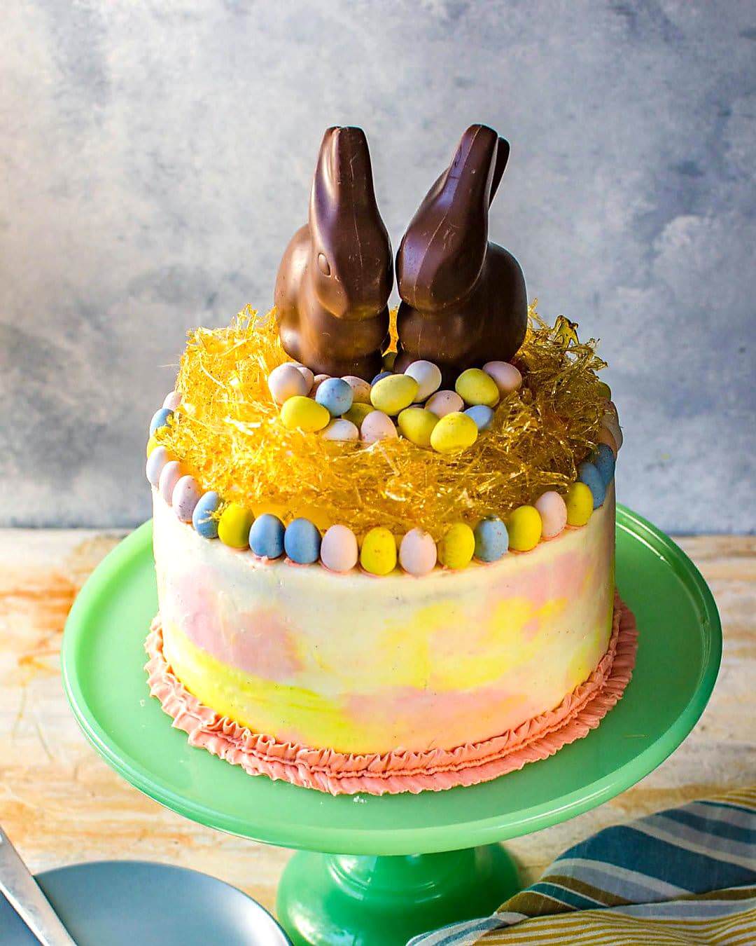 Chai and Vanilla Cake with soft, fluffy Vanilla Buttercream frosting - A spectacular swirled Easter cake with a gorgeous pastel watercolor effect, decorated with Easter eggs, chocolate bunnies and a caramelized nest on top! A sunny, happy and outrageously delicious cake to celebrate all of life's special occasions and nostalgic memories!