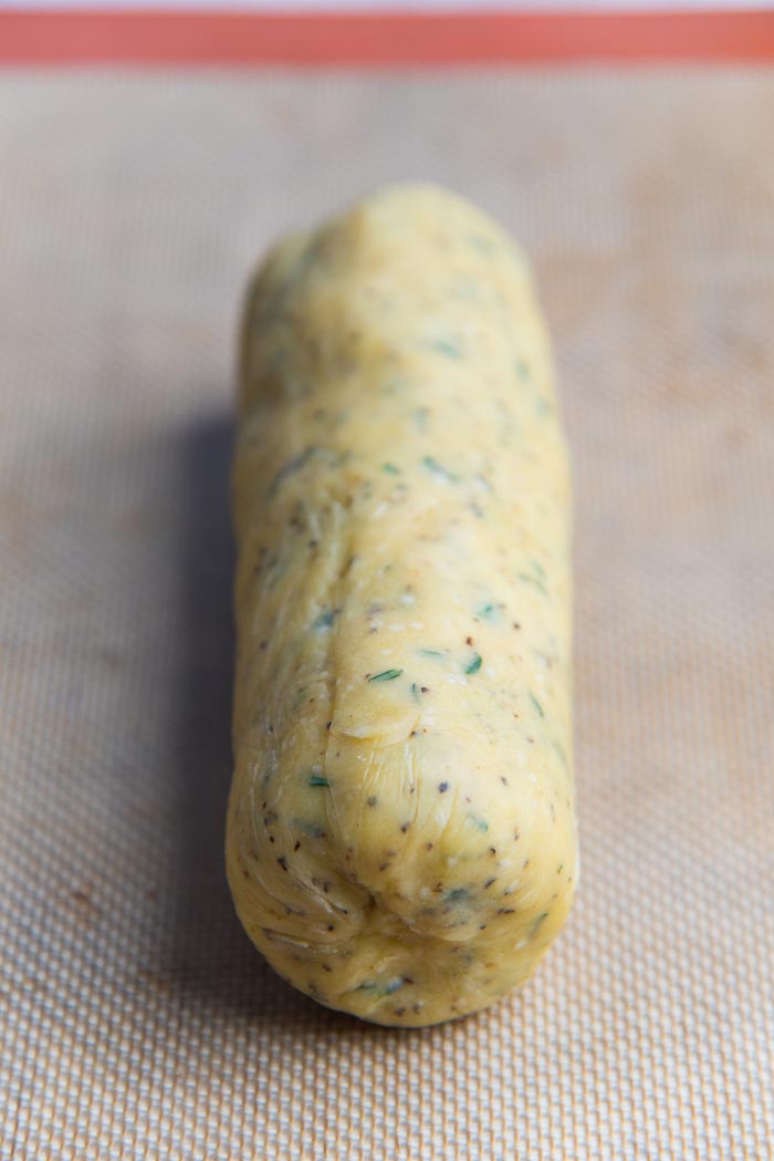 Recipe process for making thyme and cheddar cheese cookies - A refrigerated and unwrapped sliced and bake cheese cookie dough log on a silpat.