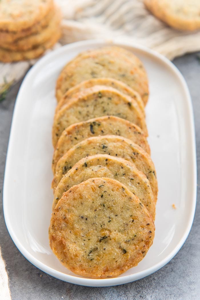 A row of savory cookies made with cheese placed on a white serving platter. 