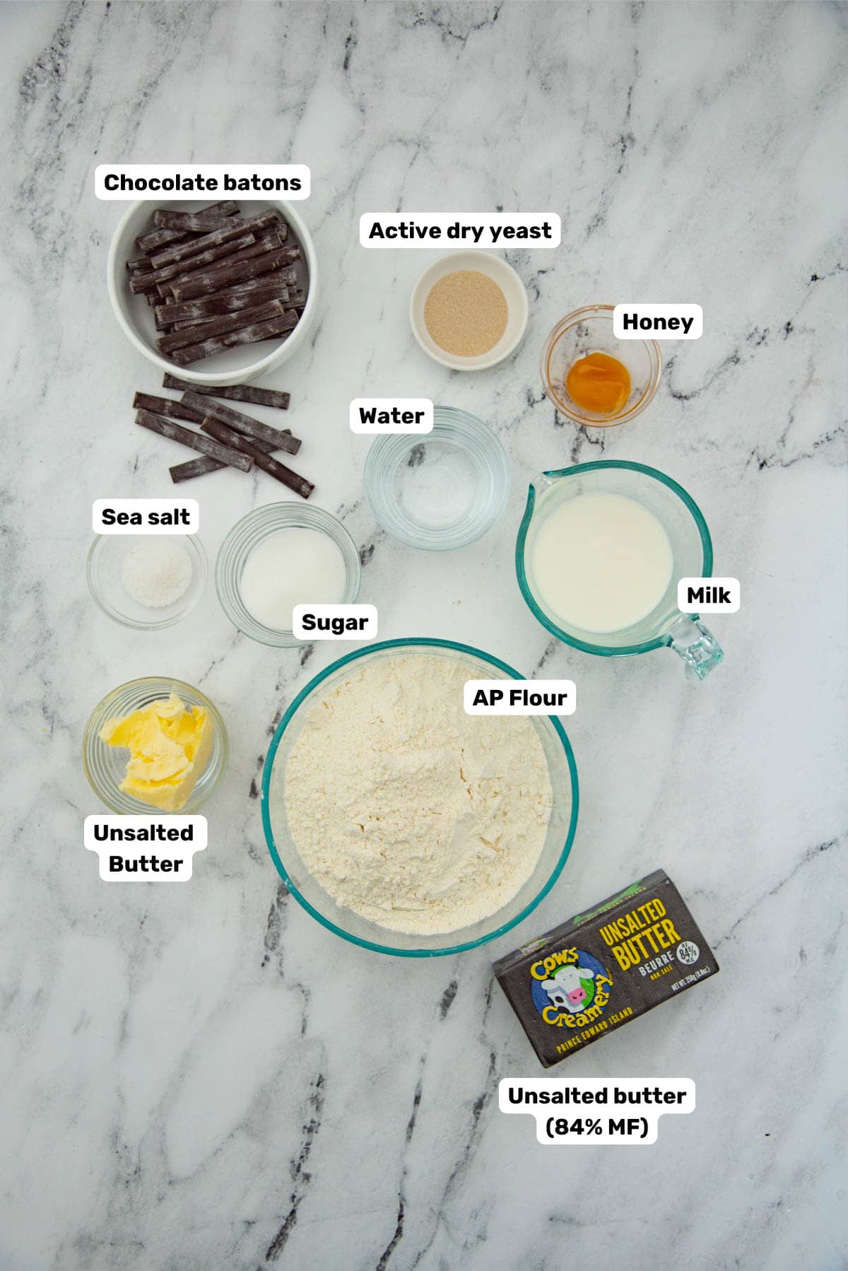 Labeled ingredients on a white background that are needed to make perfect pain au chocolat.