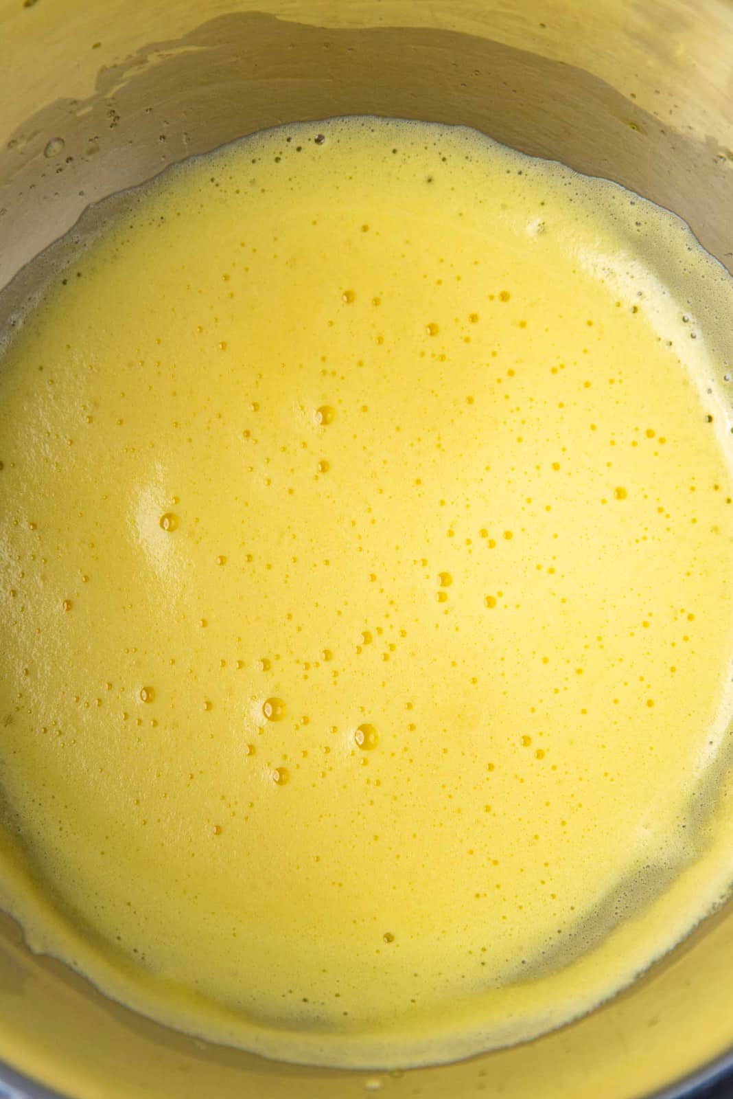 Pasteurized egg yolk mixture, for the chocolate mousse recipe. Pale yellow and frothy mix in a metal bowl