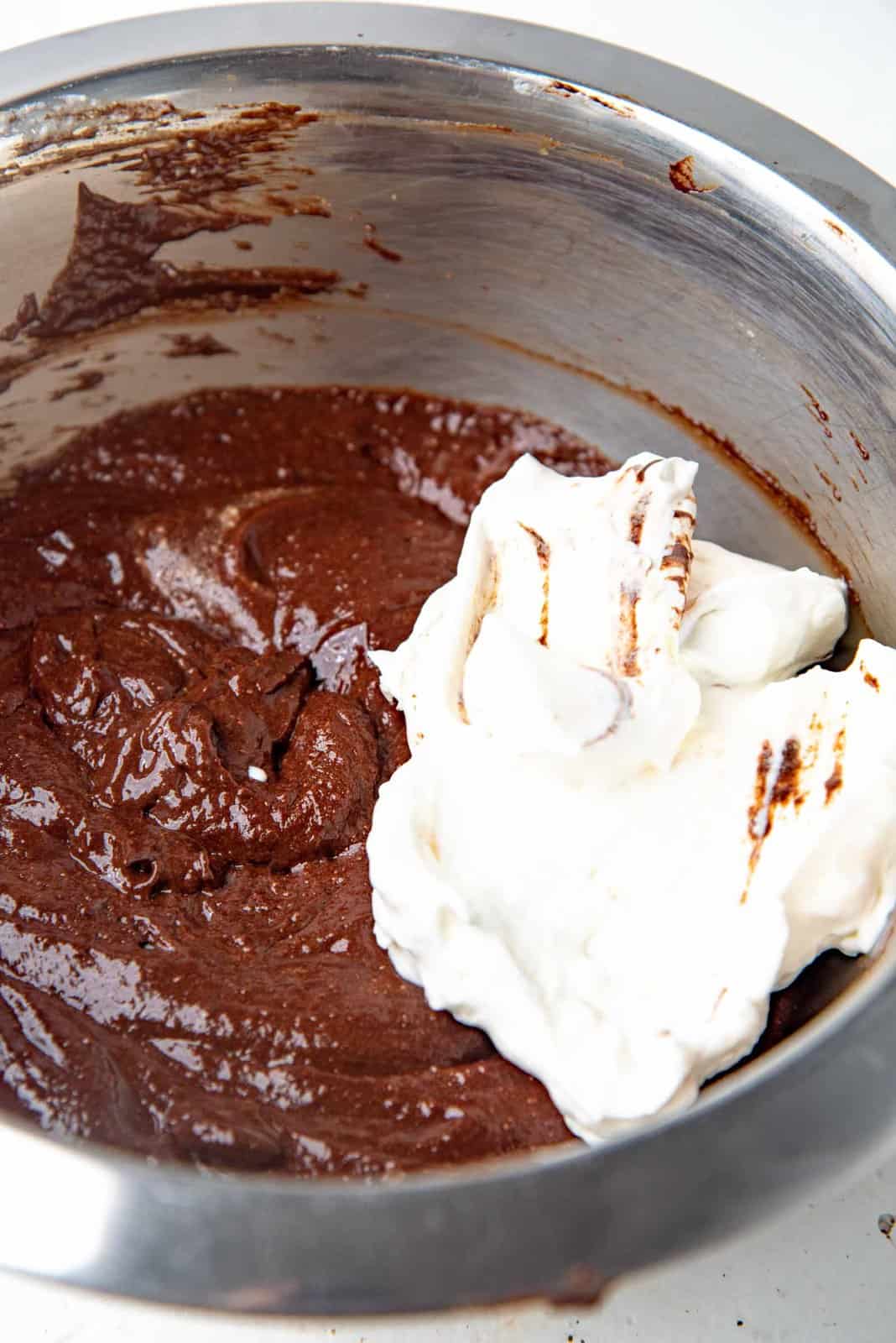 A large dollop of whipped cream on top of the chocolate mousse mixture