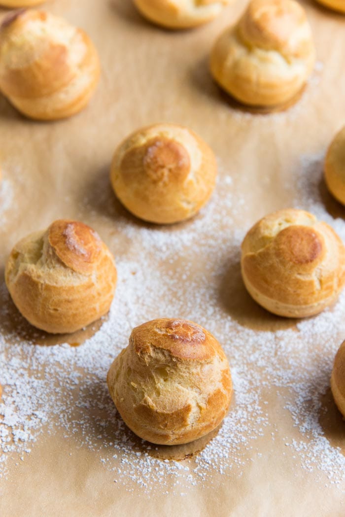 A complete guide to making perfect choux pastry - Freshly baked choux pastry "buns" on a parchment paper.