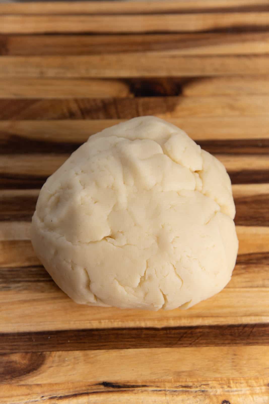 The churros dough shaped into a ball on a wooden chopping board to make authentic churros.