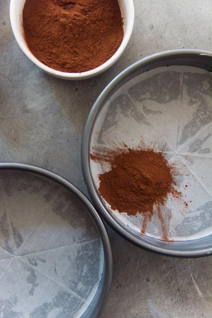 Line the bottom of the pan with parchment paper and dust the sides with cocoa powder, to prevent the cake from sticking to the pan and to keep the cake looking neat.