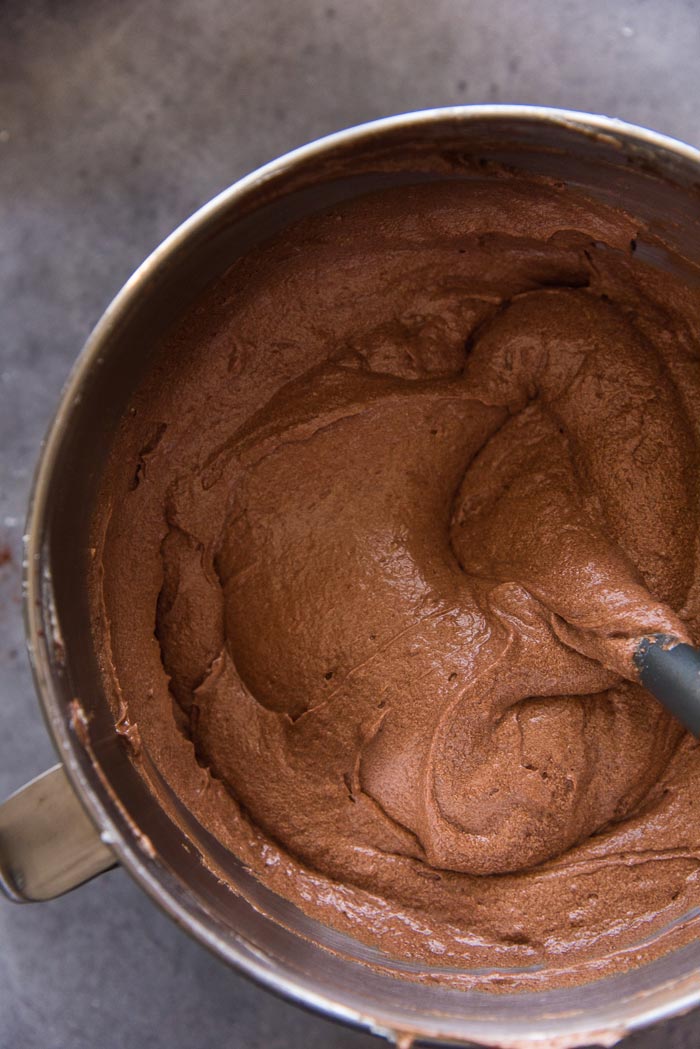 A completely mixed chocolate cake batter in the mixing bowl, with no lumps. Ready to be divided into cake pans.
