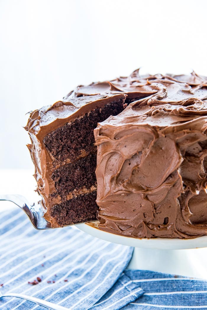A slice of the chocolate layer cake cut from the cake, and half taken out from the cake using a cake server. 