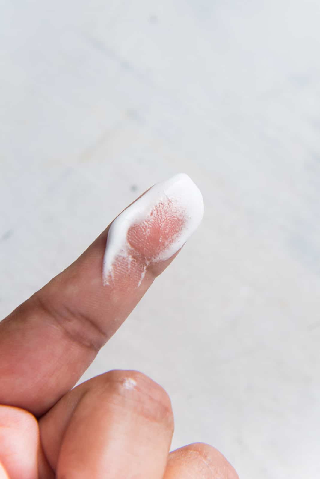 Meringue rubbed between two fingers to show sugar granules, pavlova mix is not ready at this stage