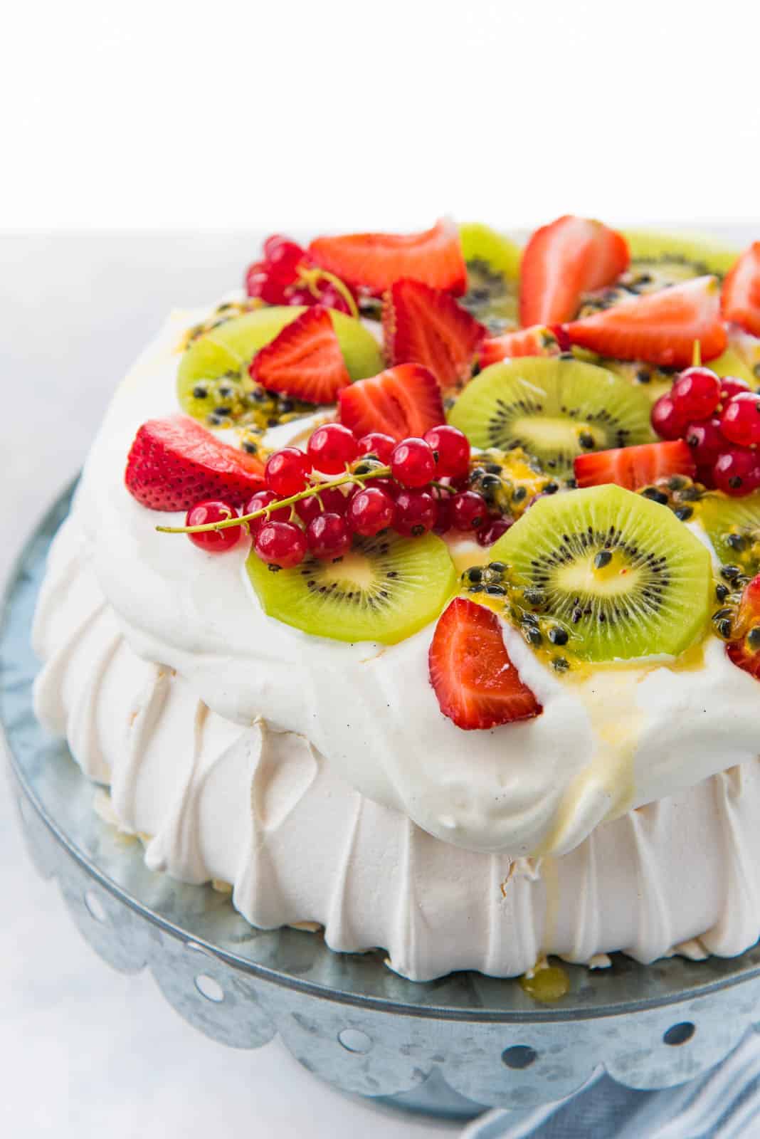 A perfect pavlova showing the whipped cream topping with fresh fruits on top