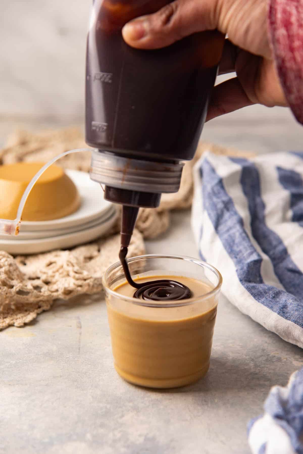 Drizzling chocolate fudge sauce over creamy coffee panna cotta.