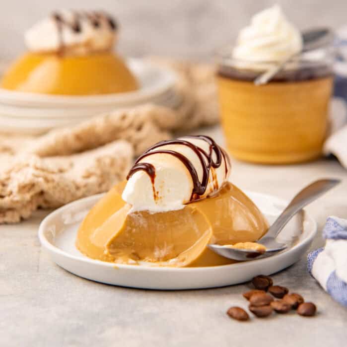 Coffee panna cotta on a plate with a scoop taken out to show creamy consistency.