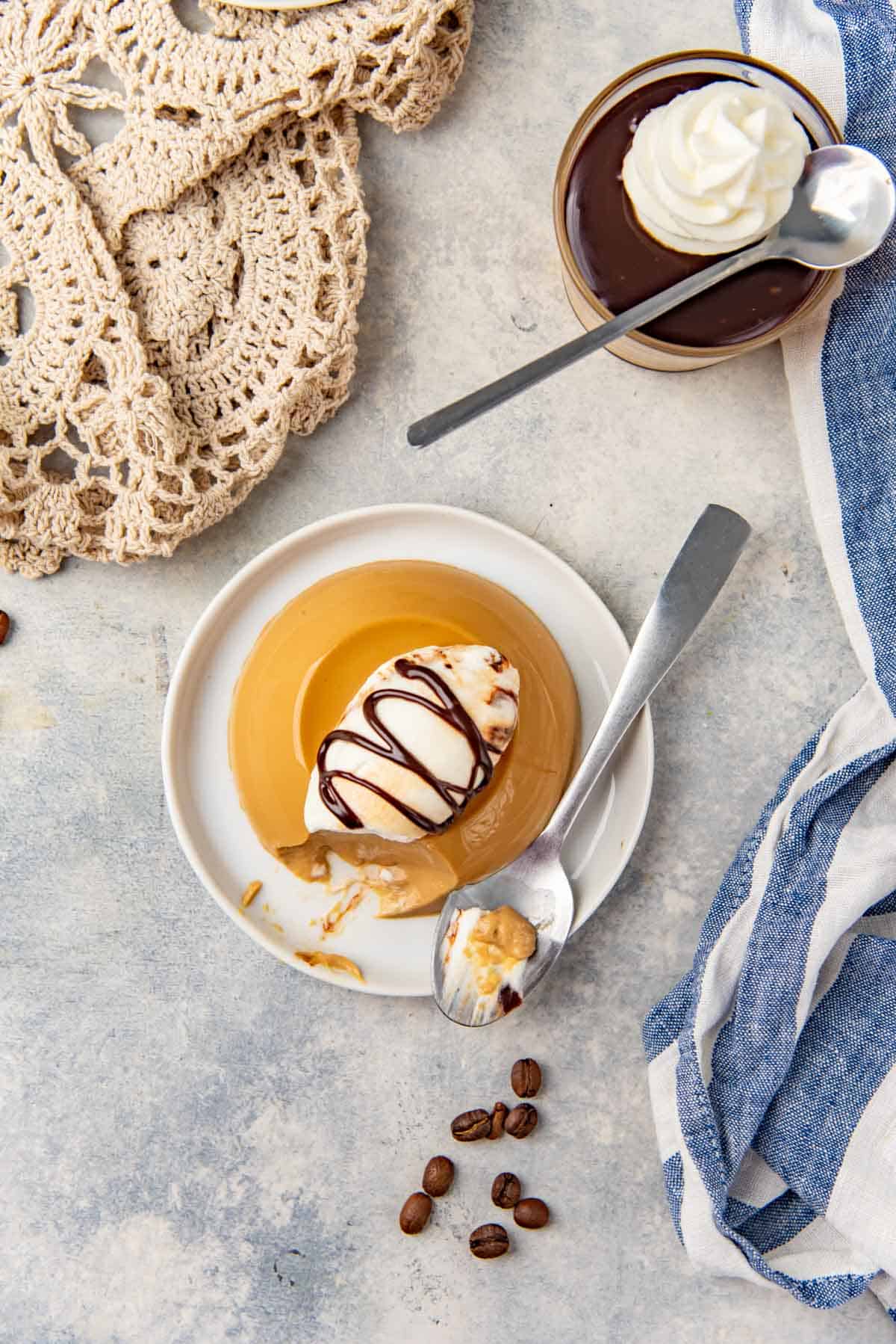 Overhead view of unmolded coffee panna cotta topped with whipped cream and hot fudge sauce.