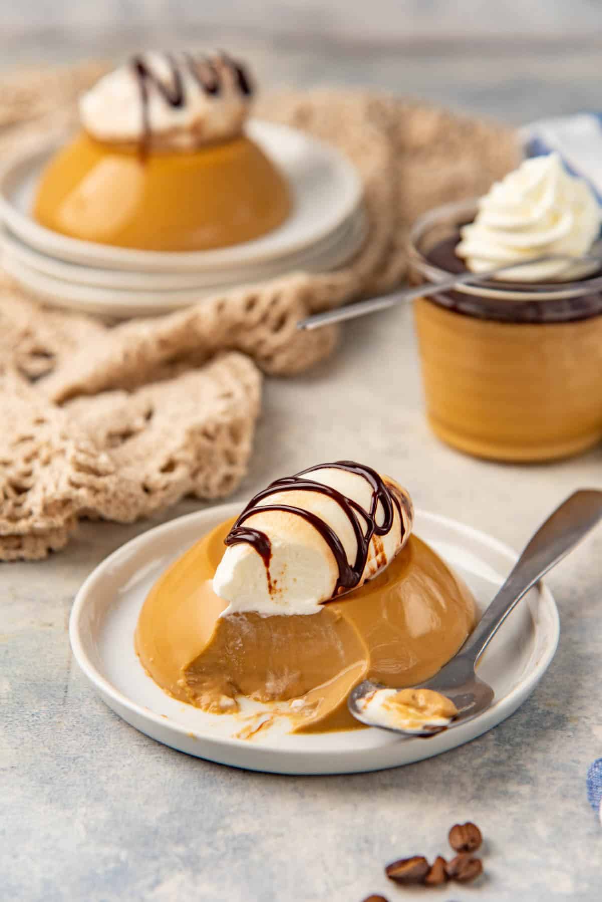Espresso panna cotta on a plate with a scoop taken out to show creamy consistency.