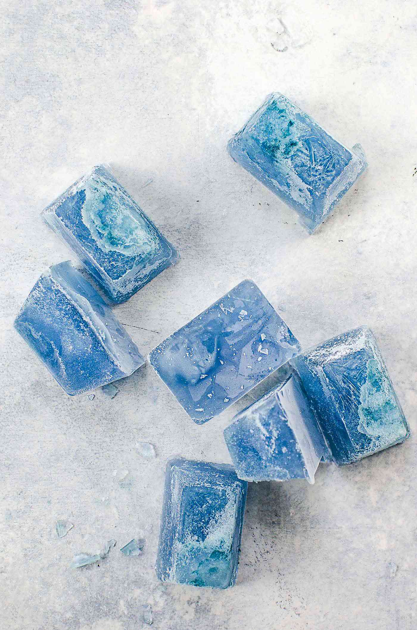 Blue ice cubes made with butterfly pea flower on a white surface.
