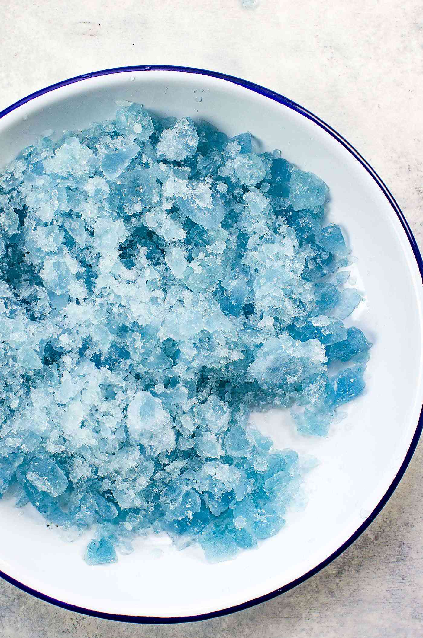 Crushed blue ice made with butterfly pea flower in a white bowl.