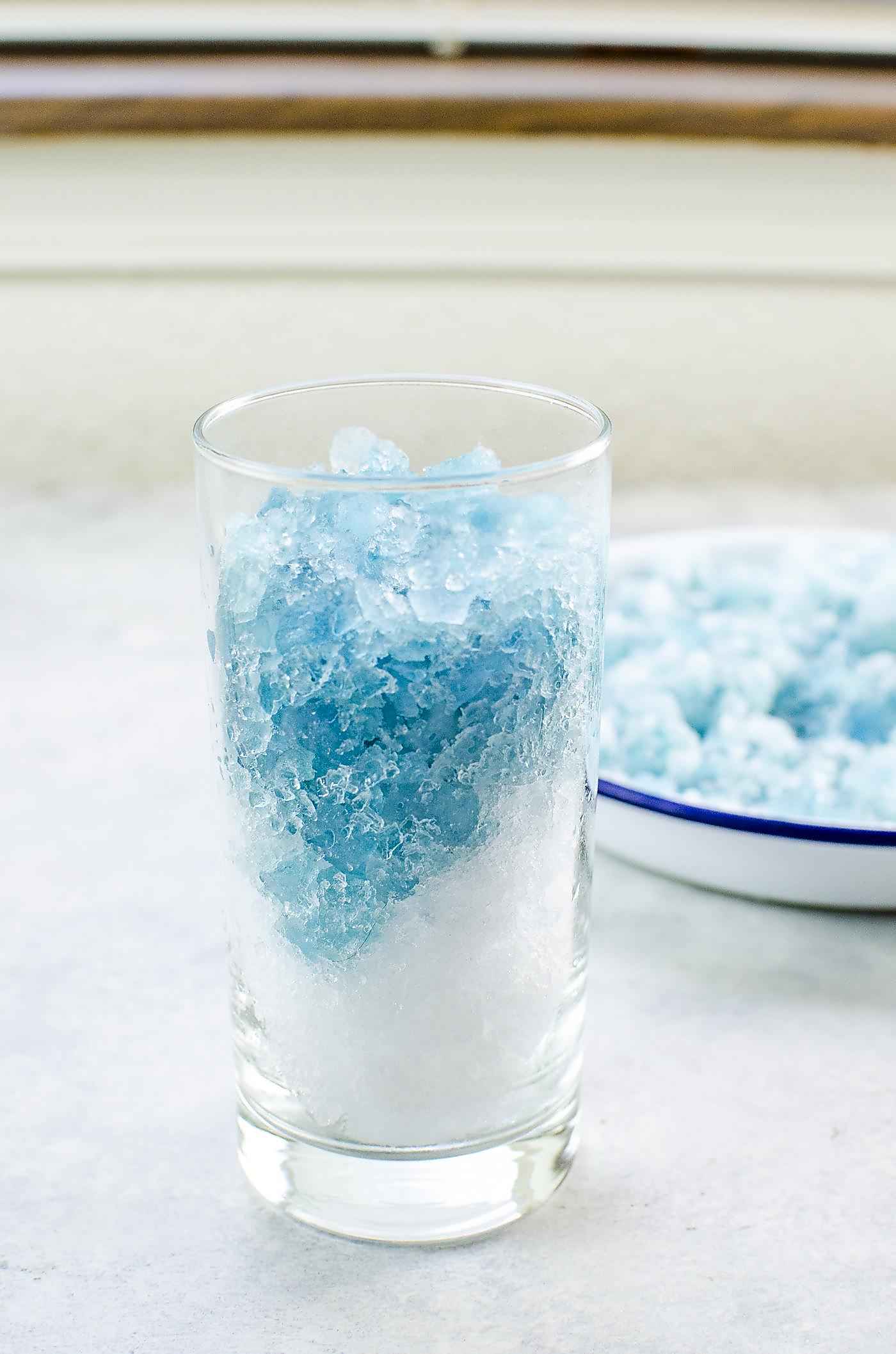 Layer of regular crushed ice and crushed blue ice in a tall glass.