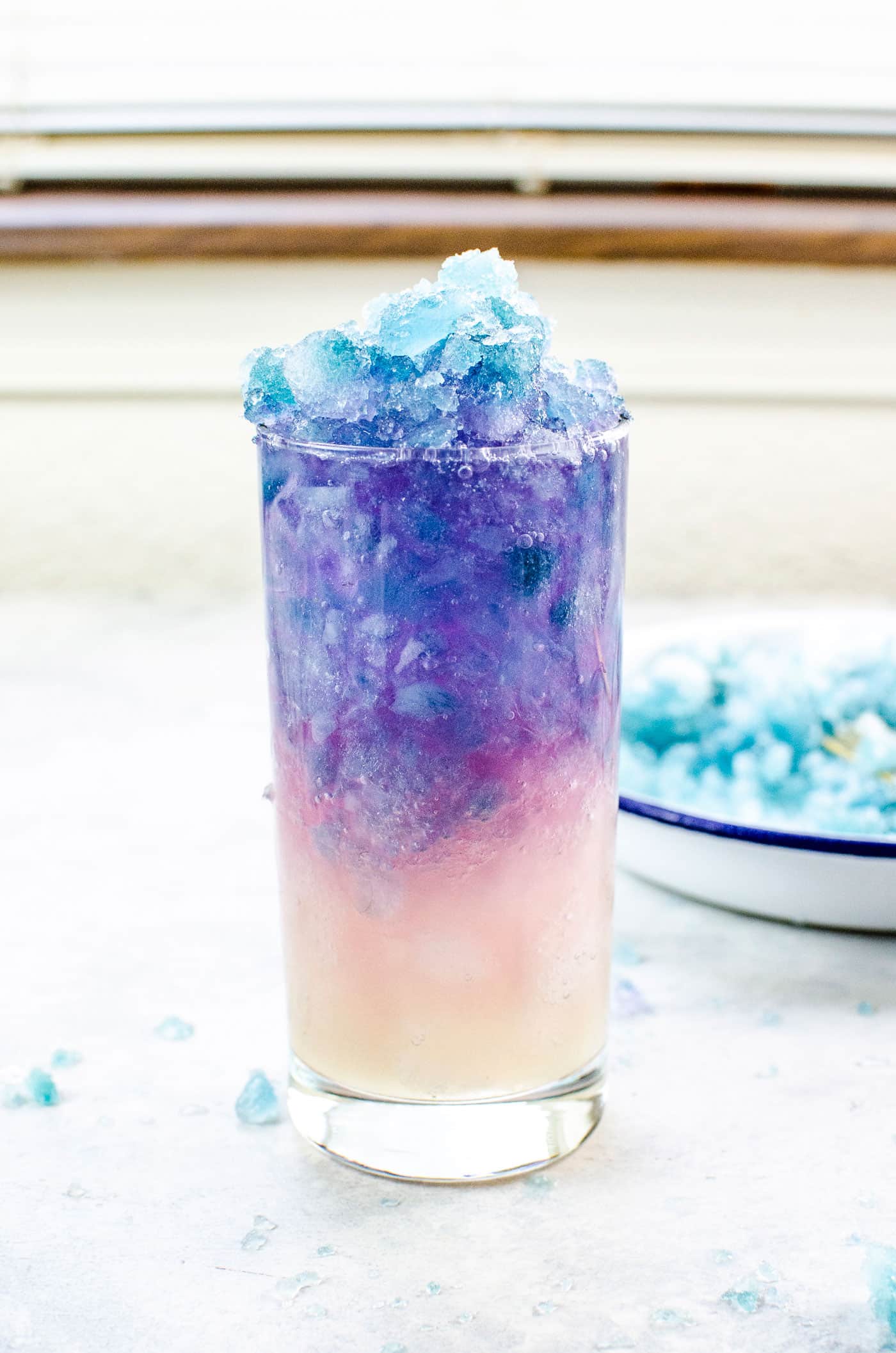 Galaxy lemonade in a glass with white, pink, purple and blue layers of crushed ice.