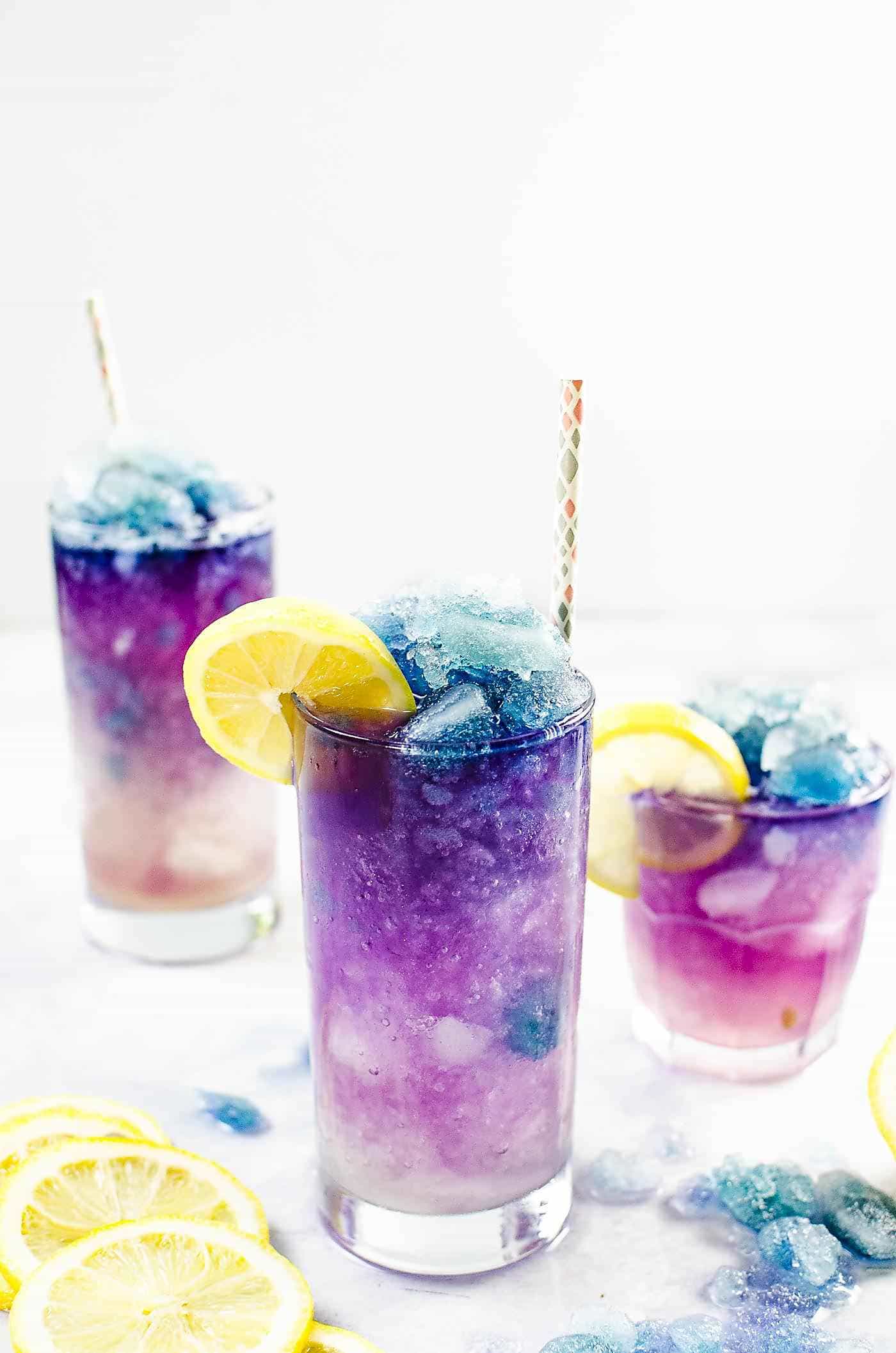 Three glasses of color changing galaxy lemonade drink with colorful crushed ice.