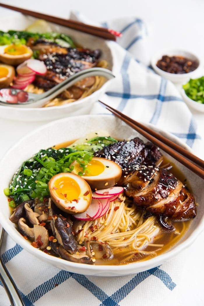 Easy Chicken ramen served in a wide white bowl, with caramelized soy chicken, ramen eggs and other toppings.