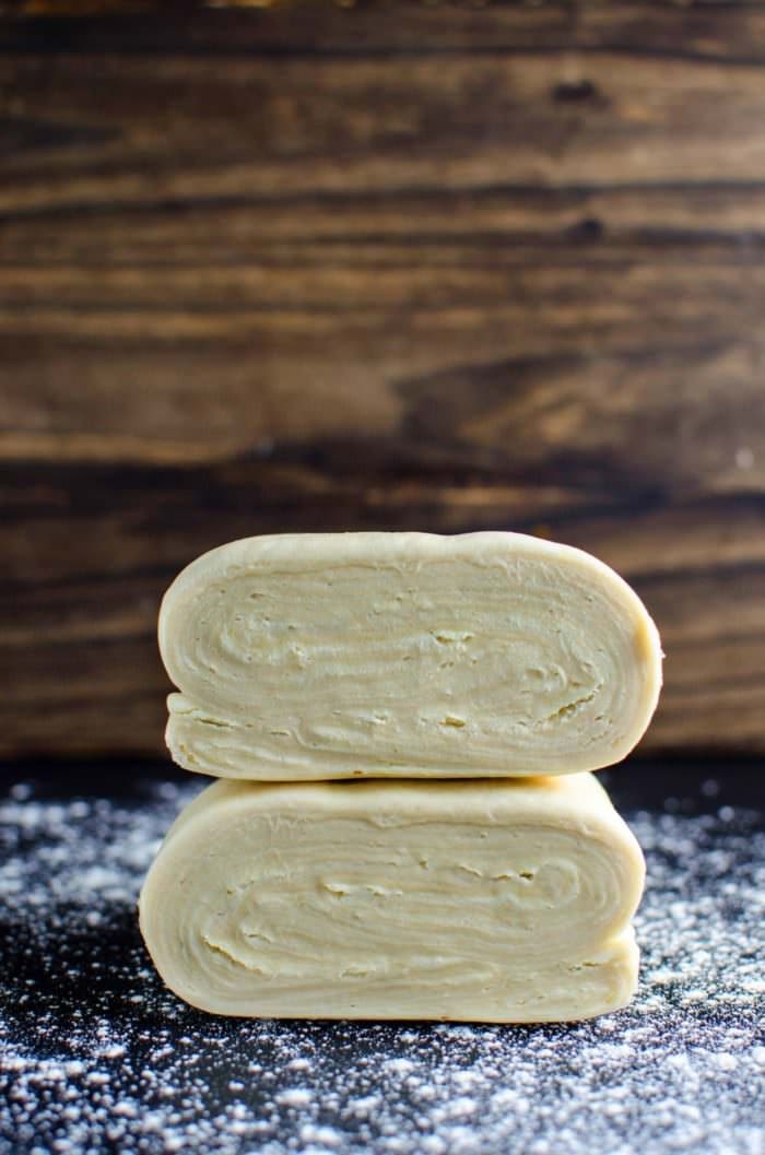 Puff pastry dough on a floured work surface, cut in half to show the layers in the middle.