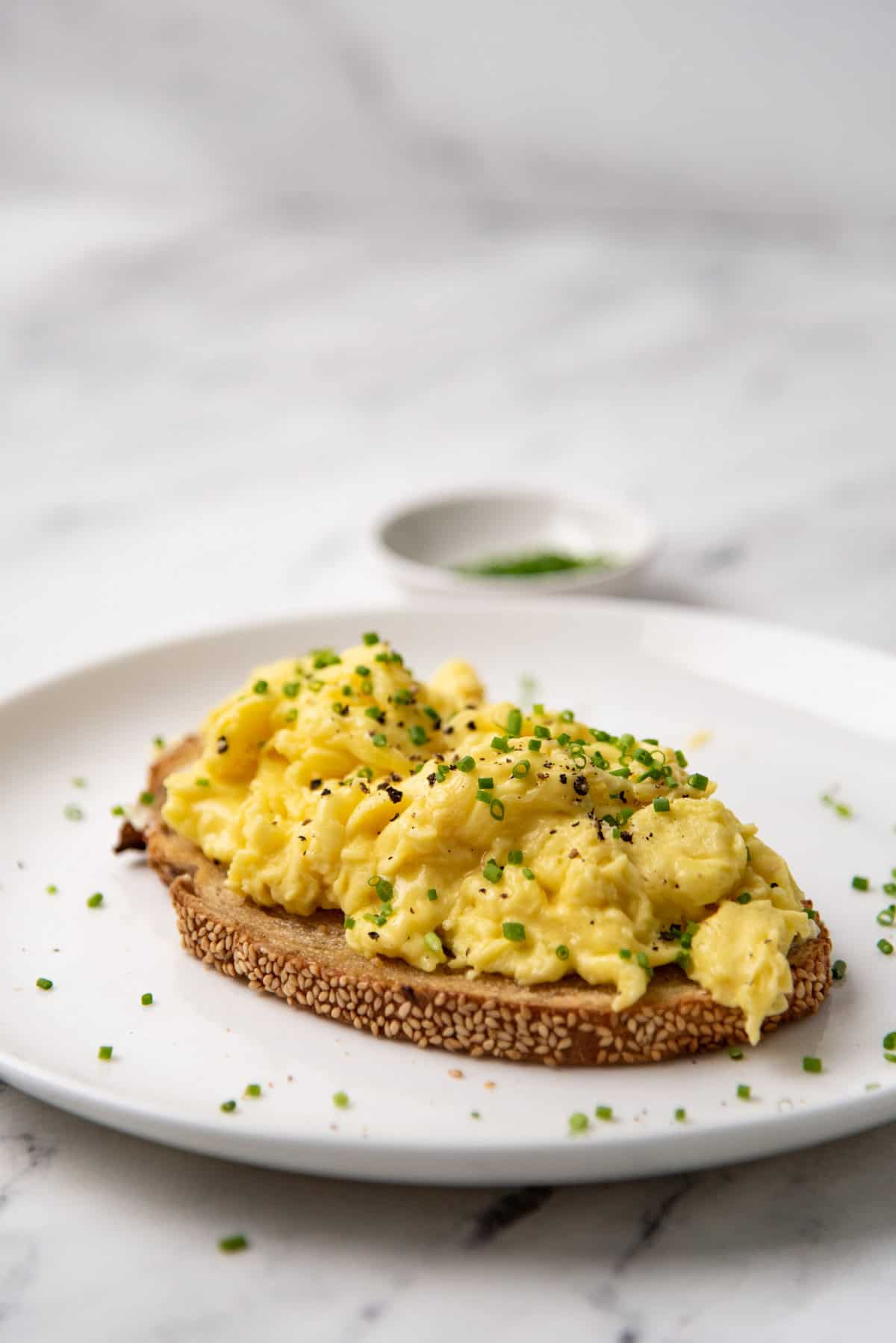 Creamy scrambled eggs serving suggestion on a toast on a white plate.