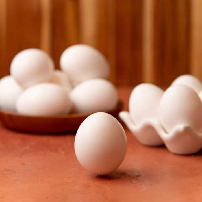 One egg placed on a table with more eggs in the background.