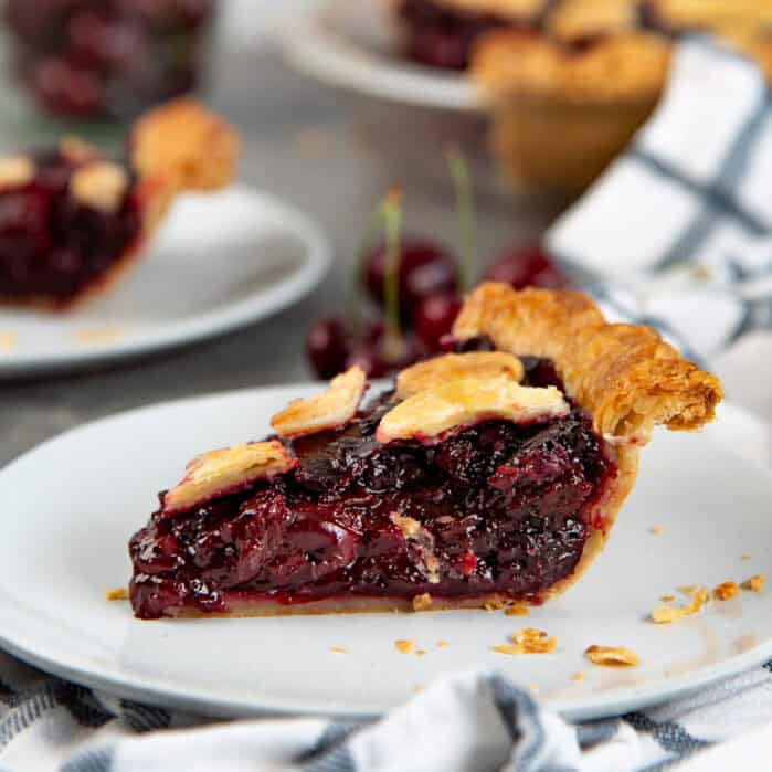 Cherry pie slice with homemade cherry filling on a white plate.