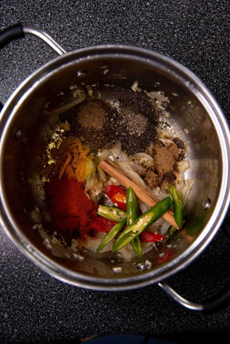 Adding curry powder and all the other spices to the softened onions in the pot