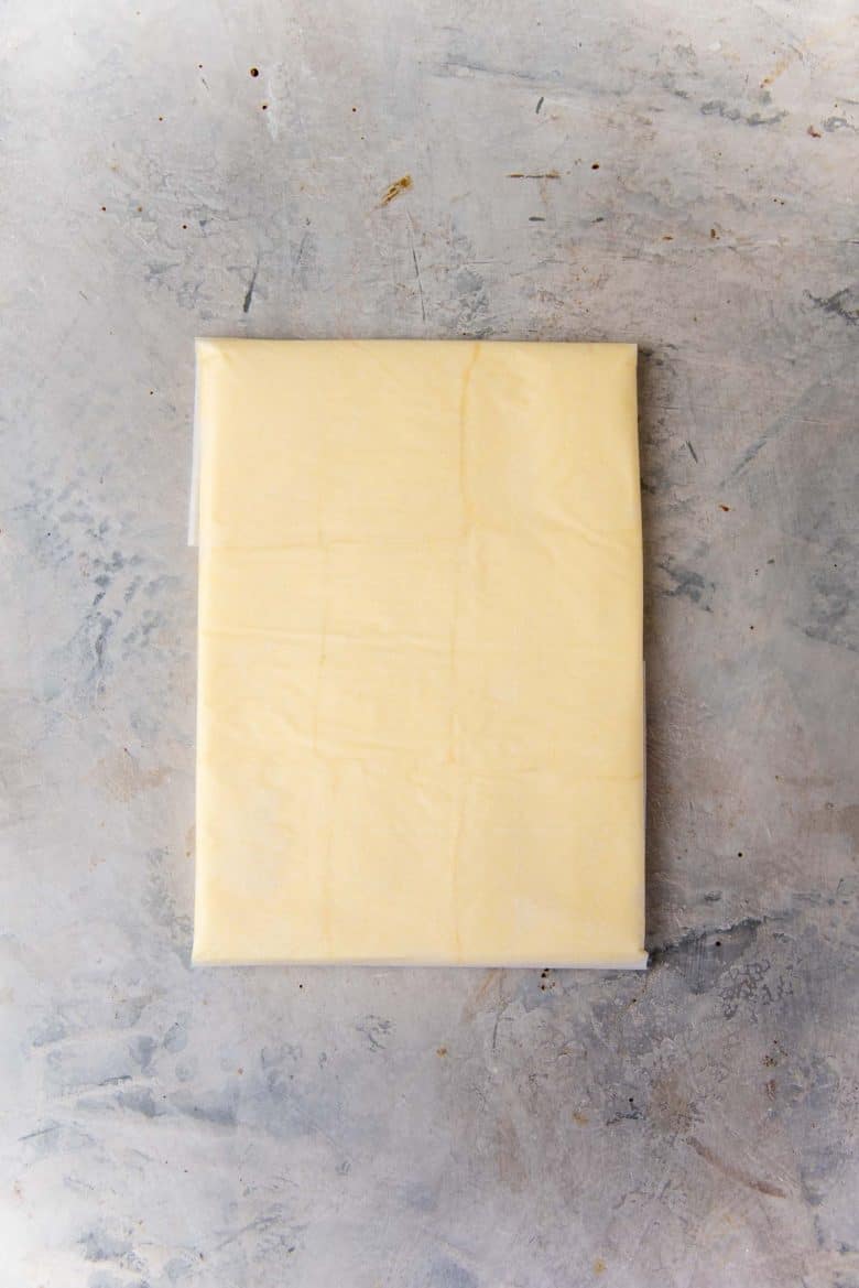 The butter has been rolled within the folded parchment paper rectangel
