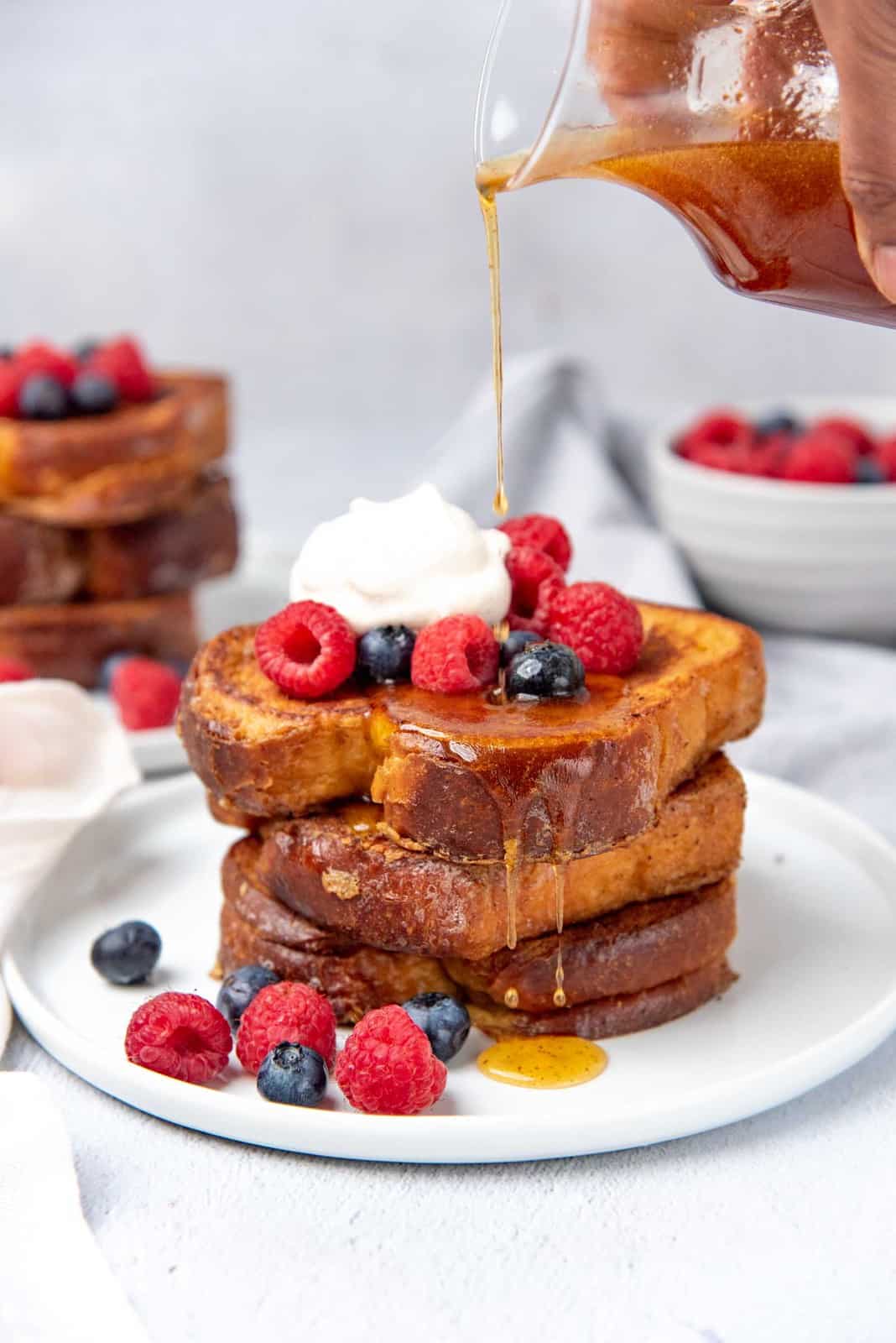 Pouring maple syrup over the stack of eggy bread