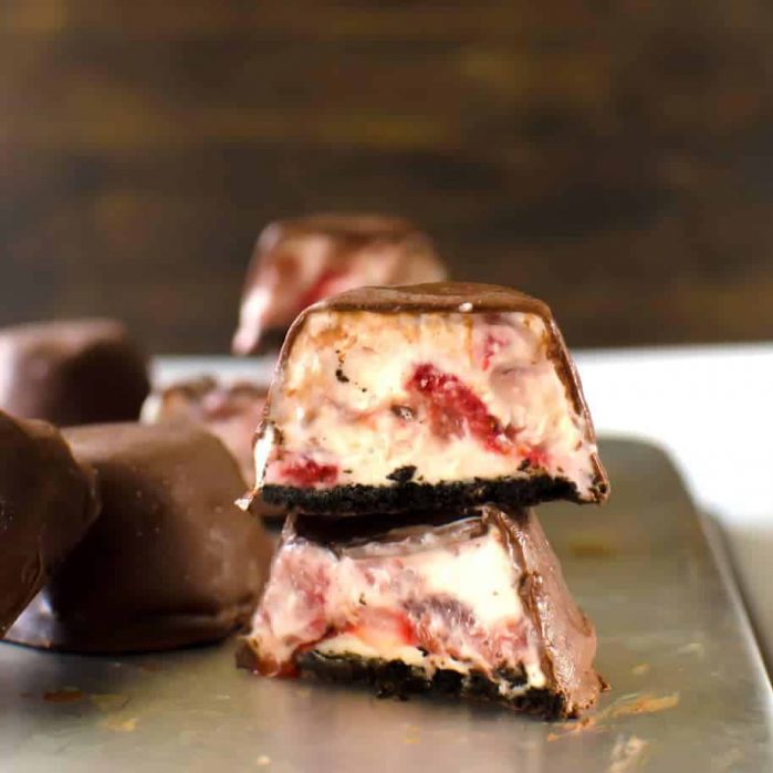 Two strawberry frozen cheesecake bites stacked on top of each other.