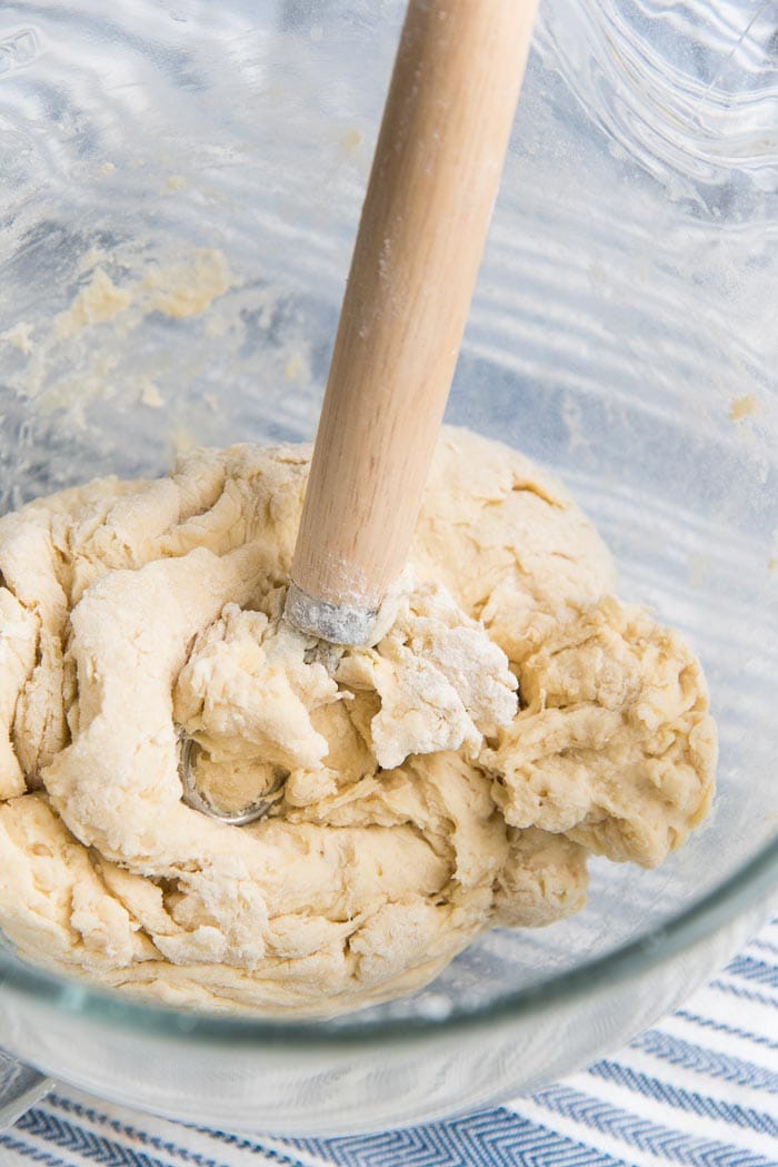 The bread dough is mixed with a dough whisk in a glass mixer bowl.