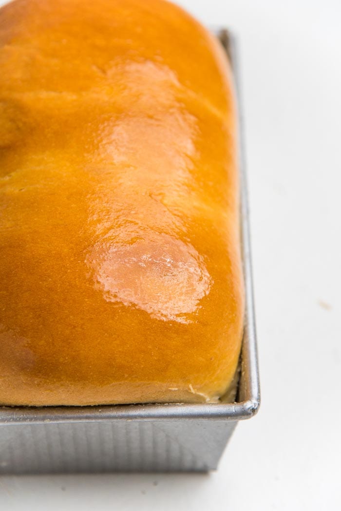 Homemade white bread straight out of the oven, with a golden crust on top.